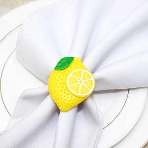 Detail of yellow lemon napkin ring with green leaves on white plate and golden edge