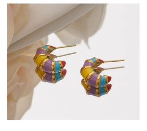 Macro shot of colorful enamel striped C-shape earrings with gold plating and mirror reflection