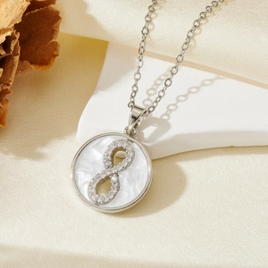 Detailed view of silver number eight necklace with crystals and white shell on stone base