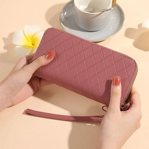 Pink quilted long wallet for women with double zipper and wristlet strap in hand
