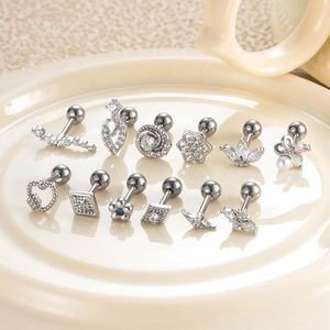Set of 12 silver stud earrings with floral and geometric designs on a ceramic tray