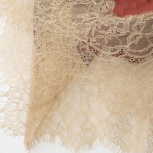 Elegant beige floral lace fabric detail with eyelash fringe on a satin midi skirt