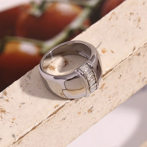 Macro view of wide silver ring with vertical baguette-cut zircons and polished finish