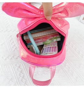 Detail view of pink sequin backpack interior with bow accent showing storage capacity