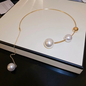 Macro detail of gold-tone tube necklace featuring elegant white irregular pearls