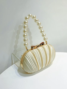Detail einer eleganten Abendtasche aus Satin mit Perlengriff und goldenem Verschluss