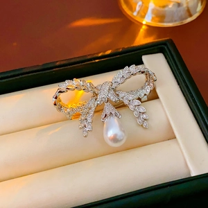 Détail macro d'une broche nœud avec diamants sertis et perle poire en boîte à bijoux
