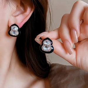 Close-up of hulu shape stud earrings with black finish and sparkling crystal inlays