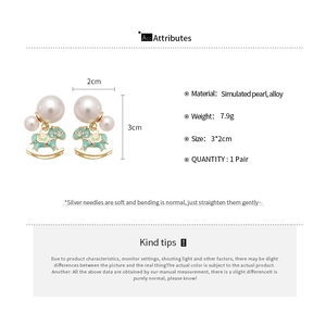 Detail view of rocking horse earrings with simulated pearl in green and gold finish