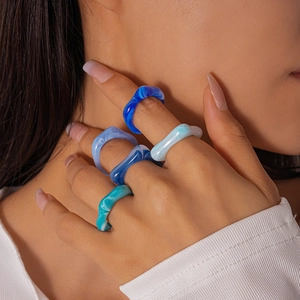Détail de cinq bagues géométriques en acrylique bleu superposées avec effet marbré
