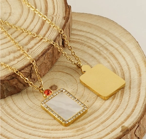Detail of gold shell pendant necklace with zircon accents on a natural wood block