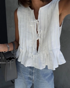 Detailed close-up of white pleated sleeveless cotton linen top with front lace-up neck knot