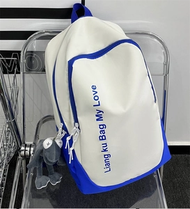 Detail of color-block canvas backpack with blue lettering and cute plush frog keychain