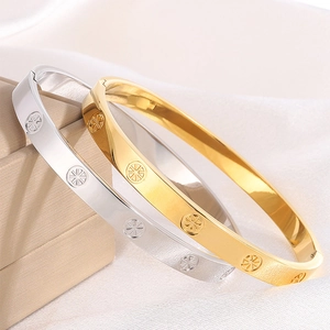 Polished gold and silver stainless steel bangles with starburst patterns on jewelry box
