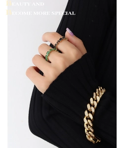Detail of gold Cuban chain bracelet with pavé diamonds and gemstone rings on hand