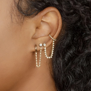 Macro view of gold tassel chain earrings with shimmering zircon pavé on a model