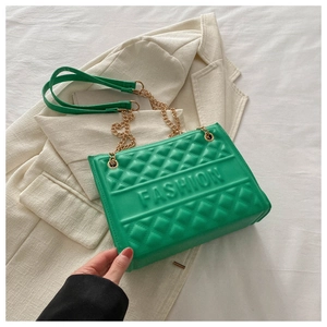 Detail of green quilted shoulder bag with gold chain and embossed fashion text