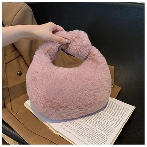 Detailed view of pink fuzzy crescent handbag held against a stylish brown blazer