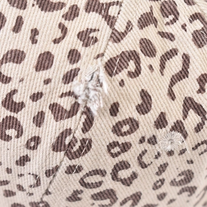 Dettaglio macro del tessuto con stampa leopardata e rifiniture strappate del cappello
