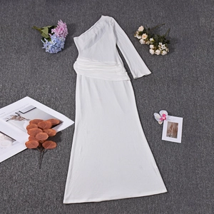 Détail d'une robe moulante blanche à une épaule et manche longue sur un tapis texturé