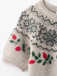Close-up of floral embroidery and geometric jacquard pattern on beige knit sweater