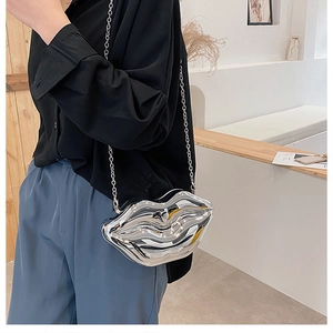Detail of silver lip-shaped hard shell crossbody bag with metallic mirror finish and chain