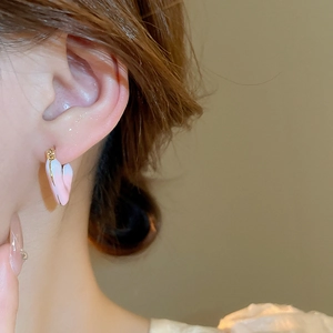 Close-up of pink and white gradient heart hoop earrings worn on a model's ear