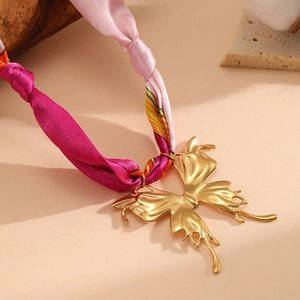 Dettaglio del ciondolo a farfalla in oro 18K con nastro di seta floreale rosa e magenta