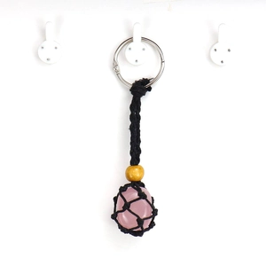 Detail of pink crystal stone inside black woven net keychain with a wood bead