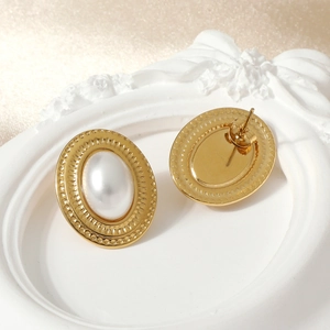 Elegant geometric gold oval earrings with white pearl inlay on a decorative tray