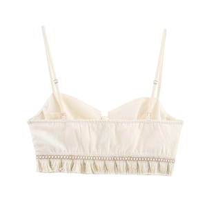 Detail of bohemian cream crop top featuring woven texture and fringe hemline