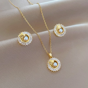 Detail of gold titanium jewelry set with pearls and zircon on beige silk background