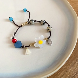 Détail d'un bracelet perlé fait main avec breloque fleur et pierres sur une assiette