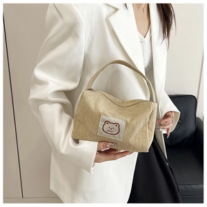 Detail of khaki corduroy handbag featuring a cute cartoon bear patch and soft texture
