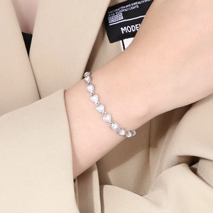 Silver heart link bracelet with mother of pearl texture shown on a model wrist