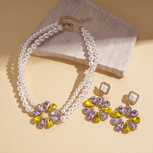 Close-up of double-layer pearl necklace and flower earrings with colored crystals