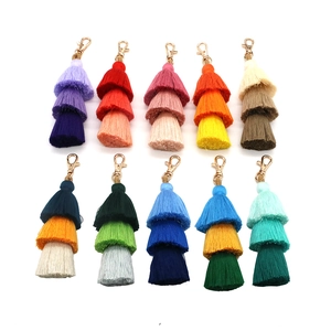 Set of 10 colorful three-tier tassel keychains with gold clasps on white background