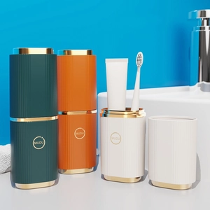 Portable travel toothbrush holder set in deep green, orange, and white with gold accents