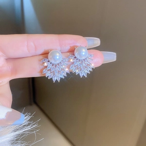 Detail shot of pearl earrings with silver wing pattern and sparkling cubic zirconia