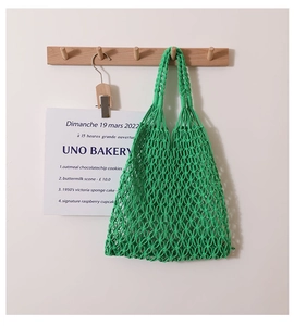 Close-up of grass green hand-woven cotton net bag with minimalist mesh structure detail