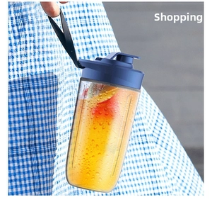 Handheld portable juicer cup with blue lid and fresh orange juice inside