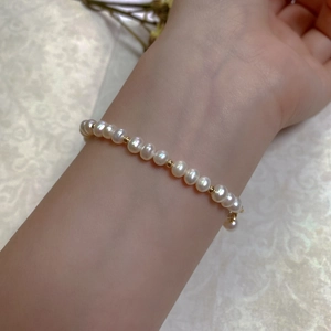Detail of a Baroque pearl bracelet with 14K gold-filled beads worn on a female wrist