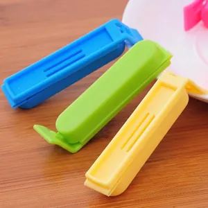 Three colorful plastic food sealing clips in blue green yellow on wood surface