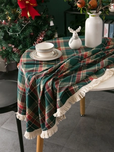 Detailed view of red and green plaid Christmas tablecloth with decorative fringe edge