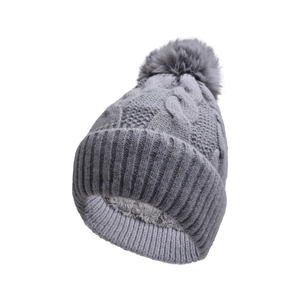 Detail of cable knit beanie with grey faux fur pom pom and warm fleece lining