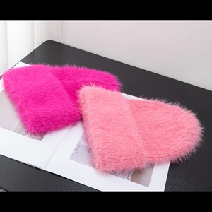 Detail view of pink fluffy knitted beanies with thick long hair texture for winter warmth
