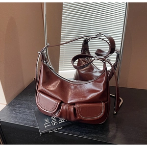 Detail of dark reddish-brown oil wax leather hobo bag with dual front flap pockets