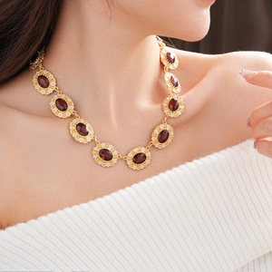 Close-up of vintage necklace with oval deep red stones and golden floral borders