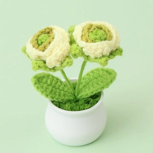 Close-up of handmade crochet rose plant in a white pot with detailed yarn texture