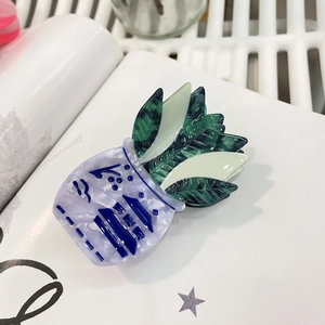 Détail d'une pince à cheveux en acétate forme plante verte avec base en porcelaine bleue